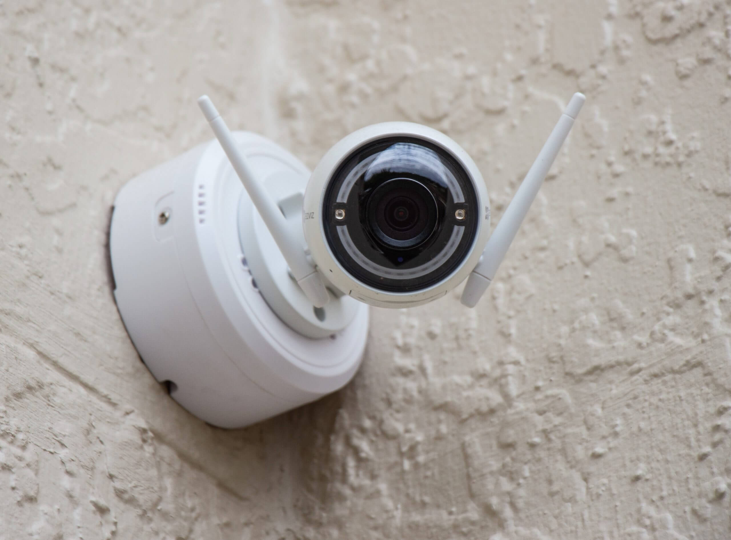 Security camera with antenna mounted within the corner of two walls.